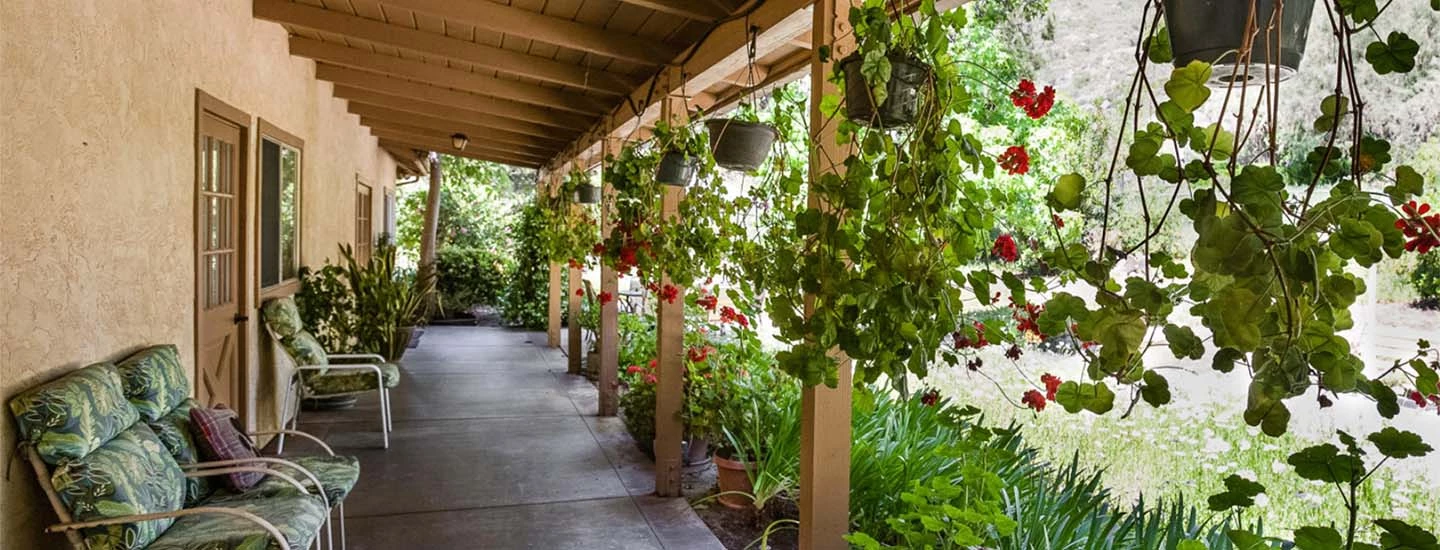 Outside corridor of Cadence at Poway Gardens with hanging baskets of plants in hallway