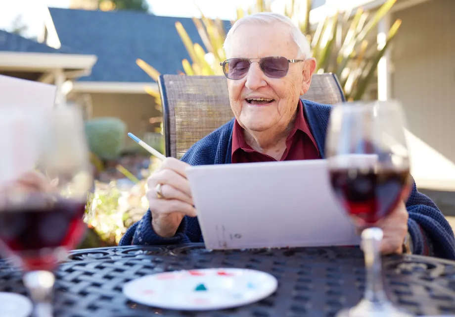 A senior man smiling as he paints outside.