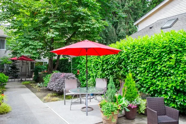 Red umbrella over chairs at out Two story senior living community with memory care in Seattle