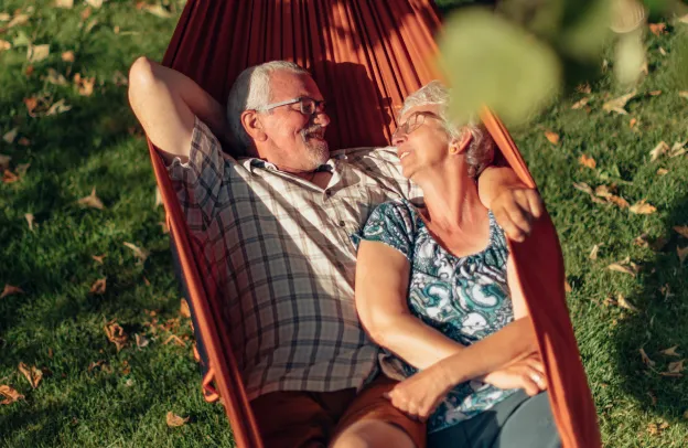 A senior couple cuddling in a hammock outside