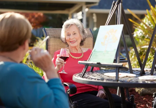 Two senior women participate in a painting class outside.