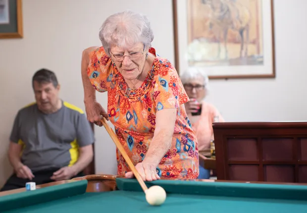 Senior woman plays pool in the game room.