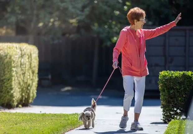 A senior woman walks her dog.