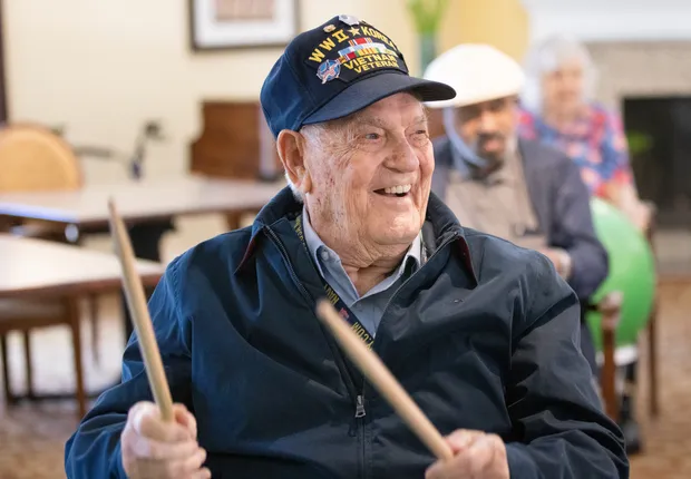 A senior veteran enjoys playing the drums.