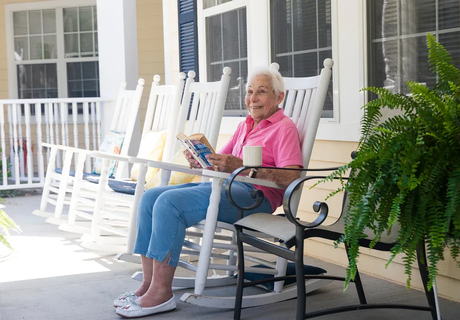 Senior living Mooresville with senior woman enjoying a rocking chair on the patio