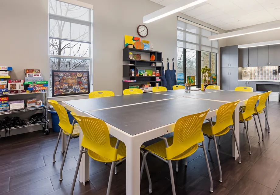 Activities room with bright yellow chairs around a large table.