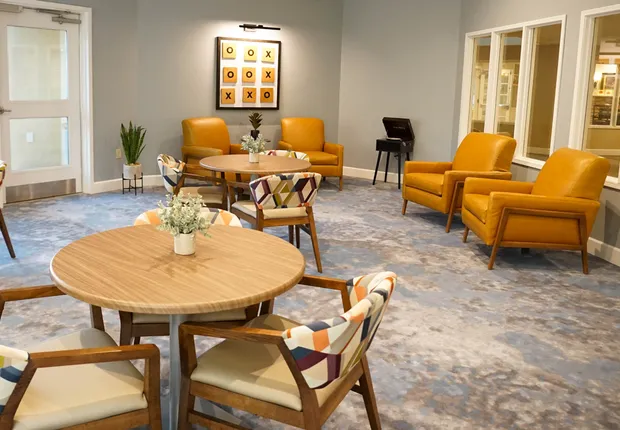Large gathering room with table and orange chairs