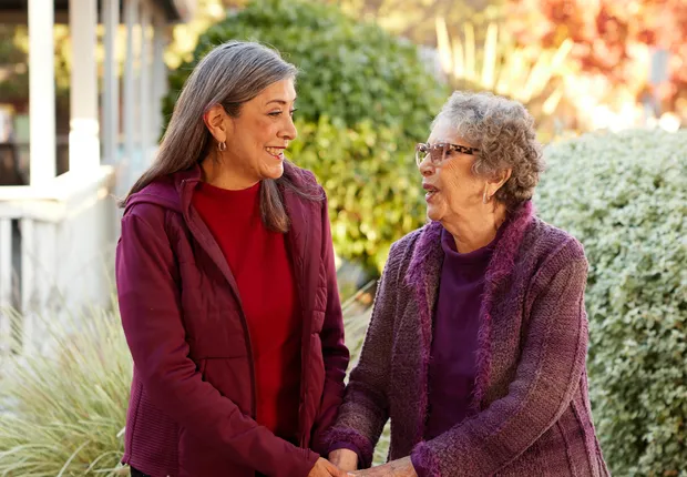 Two senior women talk while on a walk outside.