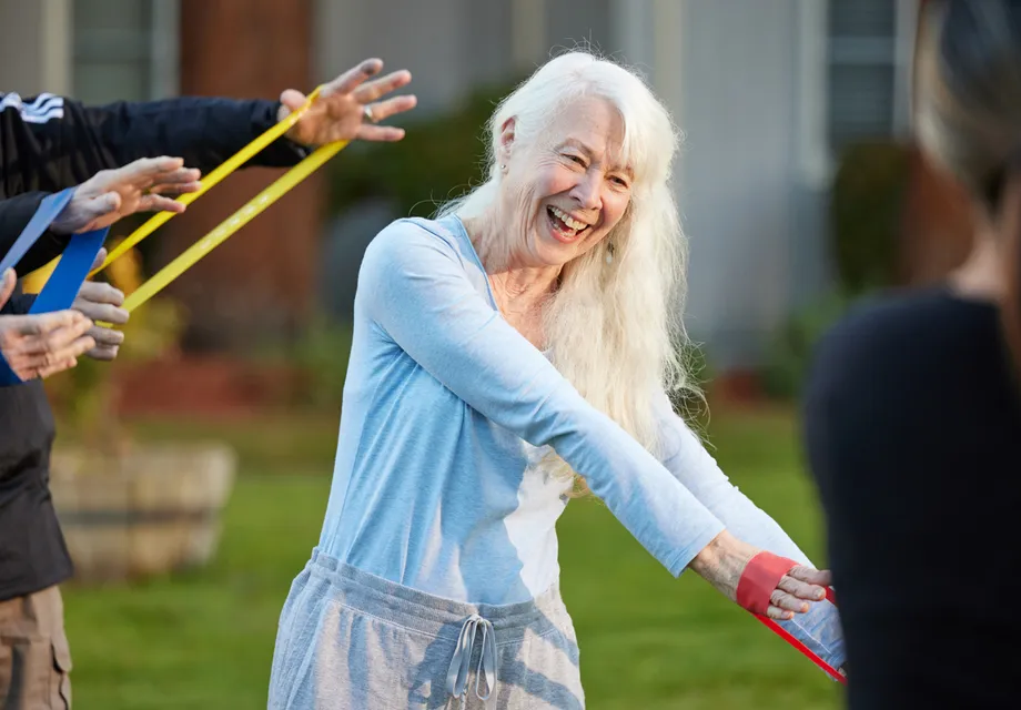 Senior woman working out with exercise bands outside.