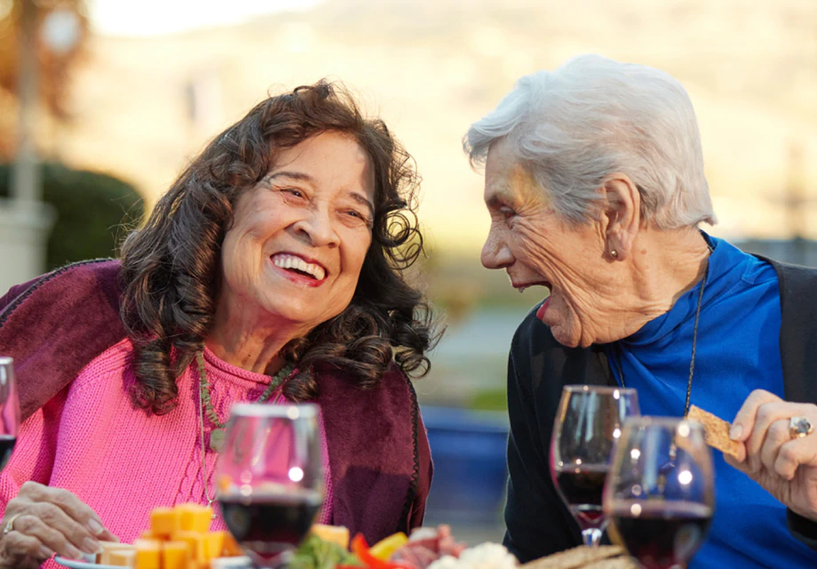 Two senior women smiling over wine