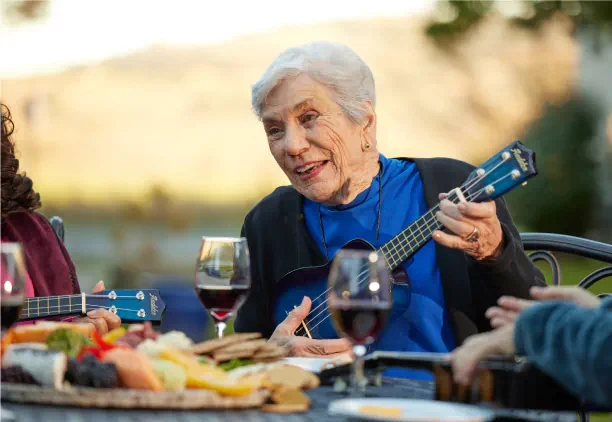 Senior woman playing the ukulele outside