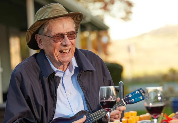 A senior man strums the ukulele at brunch