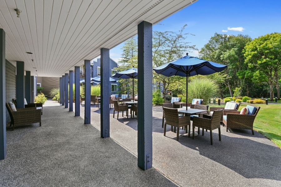 tables with blue umbrellas with green bushes in background