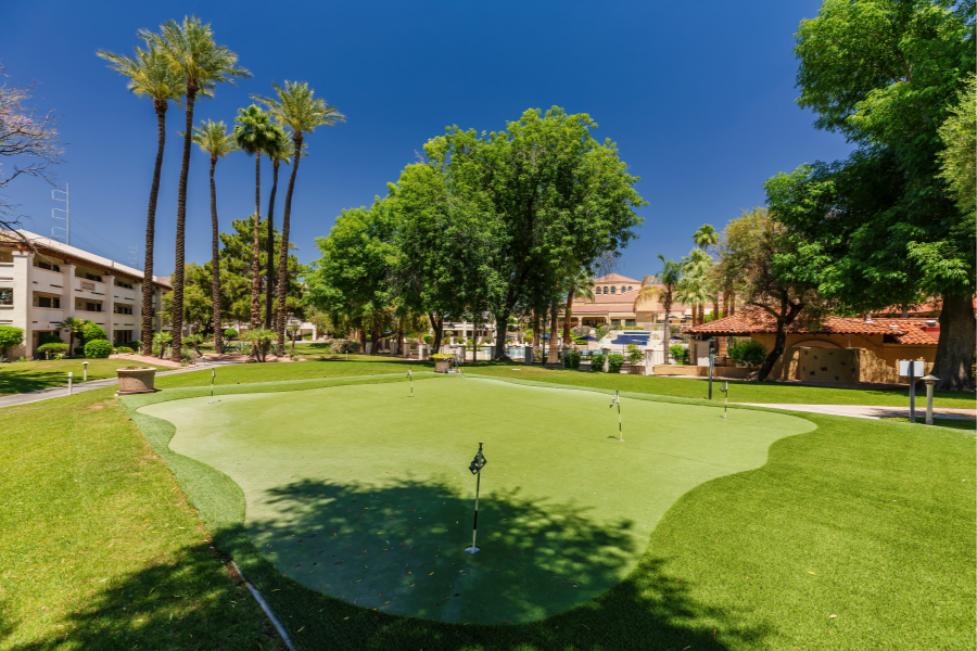 Well-maintained putting green surrounded by trees and palm trees at Park Terrace Senior Living in Phoenix, AZ.