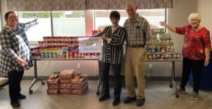 senior residents standing in front of collected canned foods