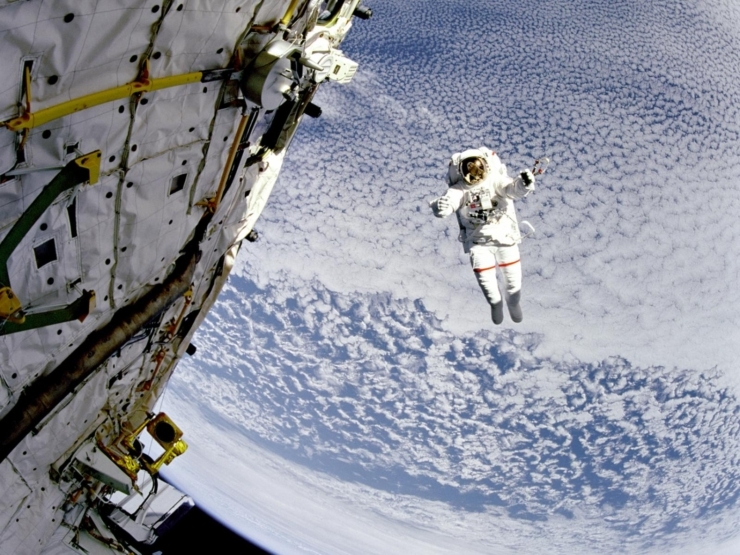 The scene captures a sense of wonder and exploration, highlighting the vastness of the sky with clouds below.