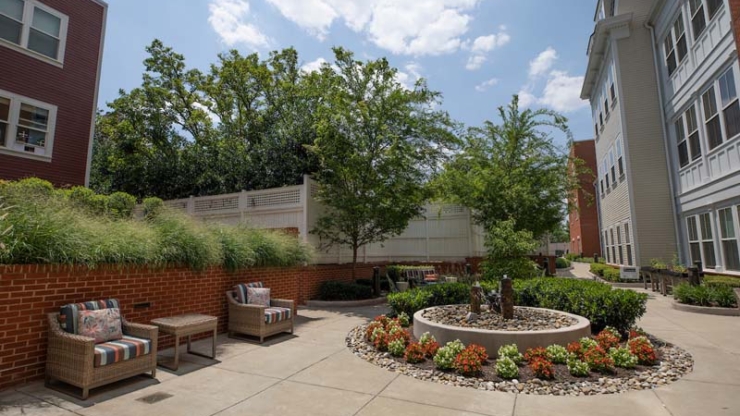 A tranquil outdoor space featuring inviting seating, lush greenery, and vibrant flowers, perfect for community gatherings.
