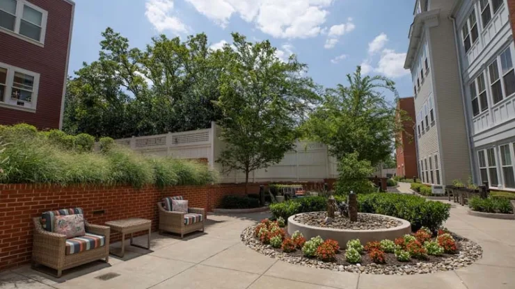 A tranquil outdoor space featuring inviting seating, lush greenery, and vibrant flowers, perfect for community gatherings.