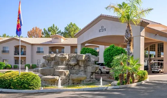 A welcoming entrance adorned with lush greenery and a tranquil fountain, inviting residents to thrive in community.