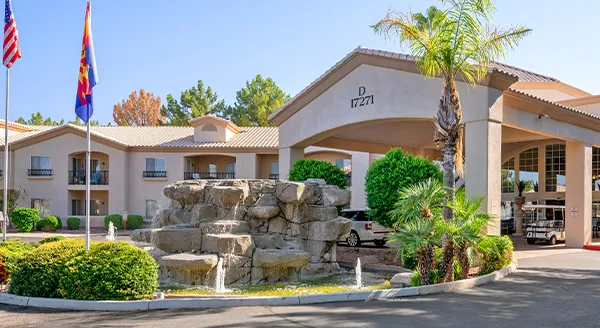 A welcoming entrance adorned with lush greenery and a tranquil fountain, inviting residents to thrive in community.
