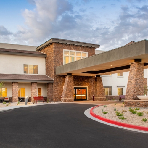 A welcoming entrance with lush landscaping and warm lighting invites a sense of community and comfort.