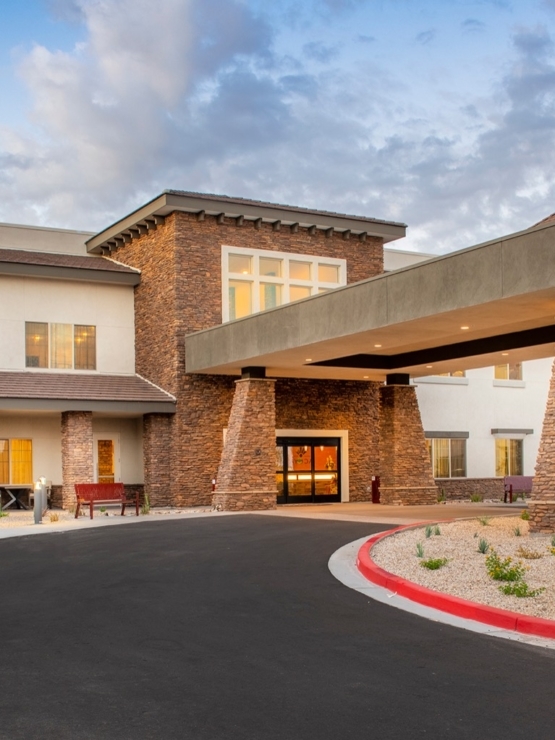 A welcoming entrance with lush landscaping and warm lighting invites a sense of community and comfort.