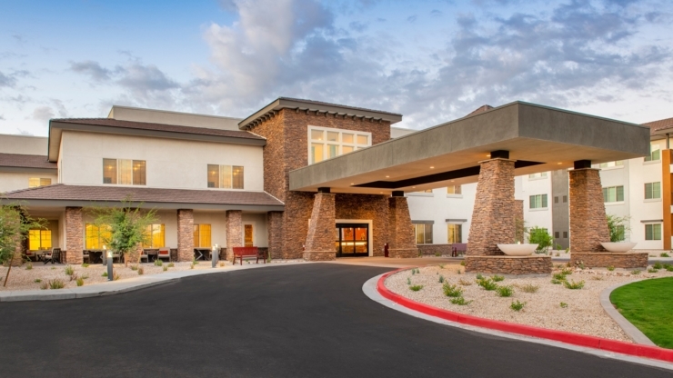 A welcoming entrance with lush landscaping and warm lighting invites a sense of community and comfort.
