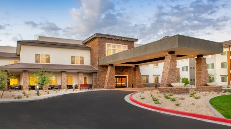 A welcoming entrance with lush landscaping and warm lighting invites a sense of community and comfort.