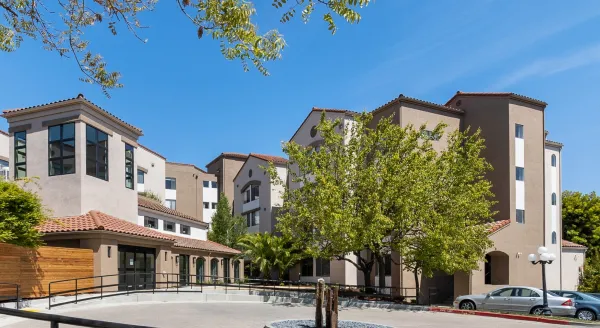 A welcoming community space, featuring lovely architecture and lush greenery under a clear blue sky.