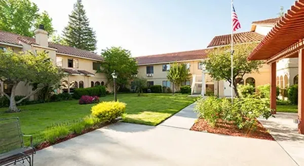 A serene courtyard welcomes residents with lush greenery and inviting pathways, fostering community and comfort.