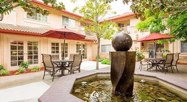 A serene courtyard invites relaxation, featuring a calming fountain, inviting tables, and shady umbrellas.
