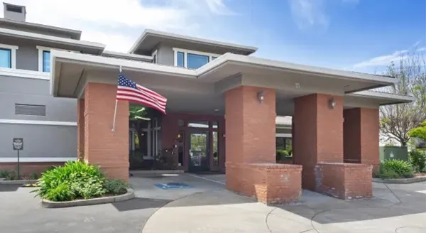 A welcoming entrance adorned with lush greenery and an American flag, inviting residents into a friendly community.