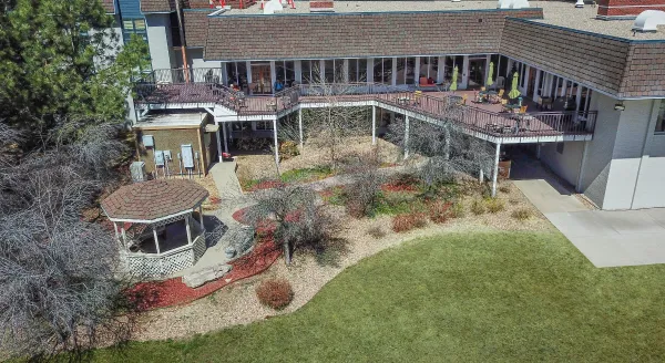 Nestled in a serene landscape, this retirement community offers a welcoming outdoor space with cozy gathering spots and lush greenery.