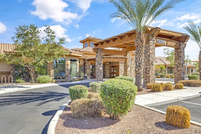 Welcoming entrance surrounded by greenery, inviting sunlight, and a sense of community at the forefront.