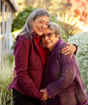 A joyful embrace between two women, surrounded by a lush garden, radiates warmth and community spirit.