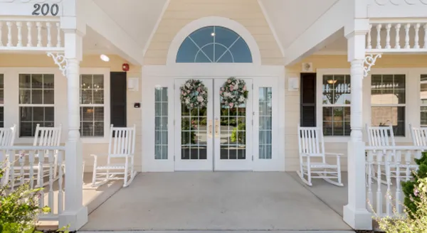 Welcoming entrance with charming rocking chairs and beautiful floral accents, inviting community warmth.