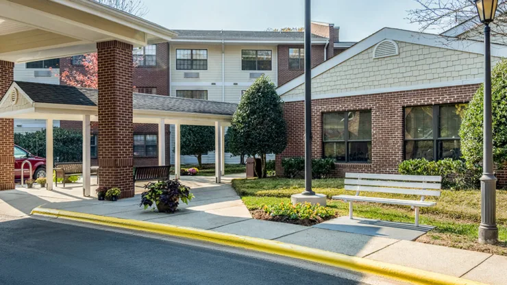 A welcoming entrance with lush greenery, inviting benches, and a warm, sunny ambiance fosters community spirit.