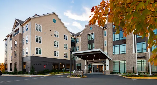 Warm and inviting, this retirement home features a welcoming entrance amidst vibrant autumn leaves.