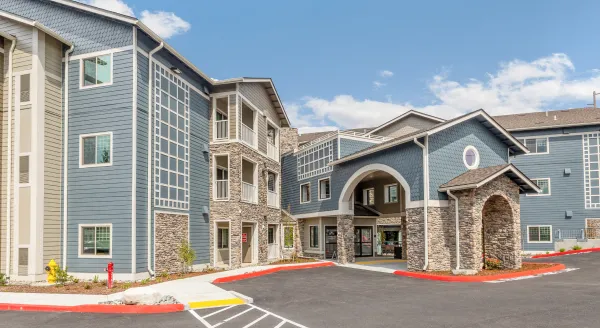 A welcoming retirement community with modern architecture, surrounded by beautiful landscaping and natural light.