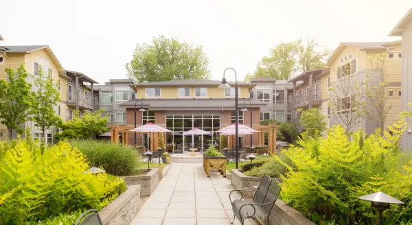A welcoming garden pathway leads to a vibrant community hub, surrounded by lush greenery and seating areas.