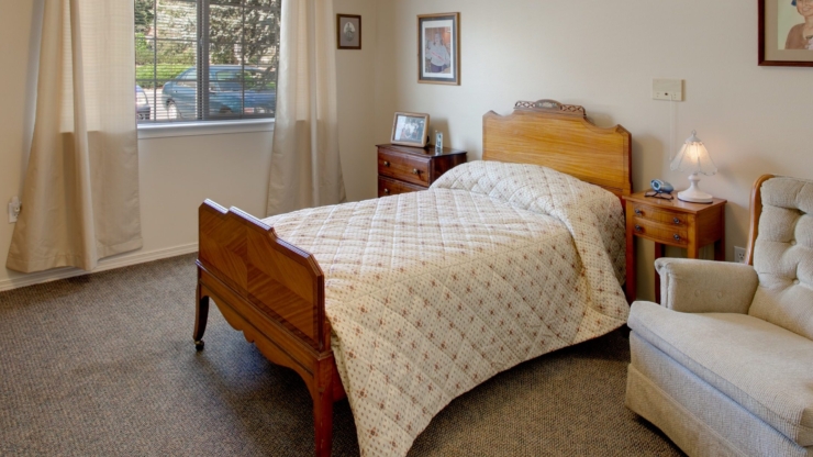 A cozy, inviting room featuring a comfortable bed and soft seating, perfect for relaxation and community.