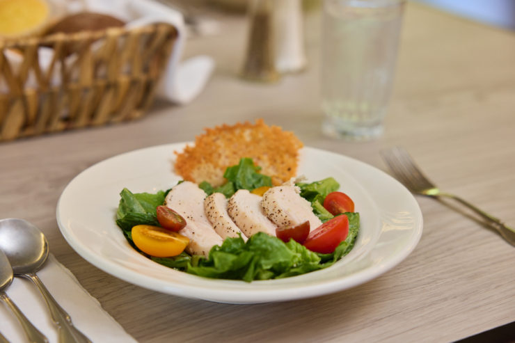 A beautifully plated salad, featuring tender chicken and fresh vegetables, awaits. A warm atmosphere invites community and connection.