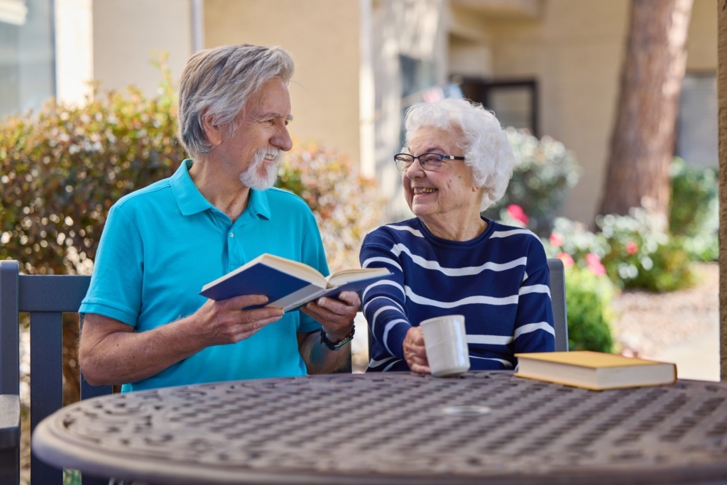 A joyful couple shares laughter over a book and coffee, embodying warmth and community spirit.