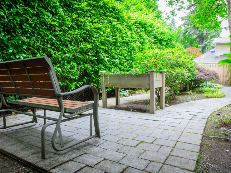 A serene garden path invites relaxation, framed by lush greenery and a welcoming bench.