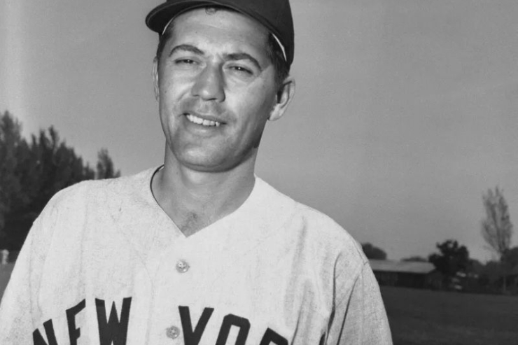 A smiling man in a baseball uniform stands in a sunny park, exuding a sense of joy and community.