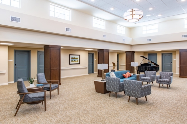 A bright, inviting common area with comfortable seating and a piano, perfect for community gathering.