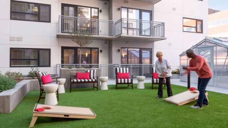 Engaging residents enjoy a lively game outdoors, surrounded by vibrant seating and lush greenery.