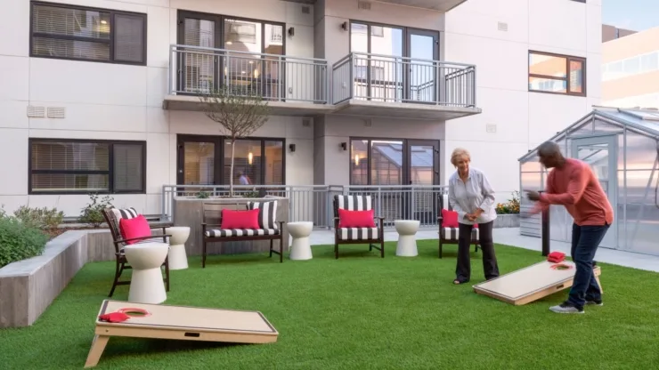 Engaging residents enjoy a lively game outdoors, surrounded by vibrant seating and lush greenery.