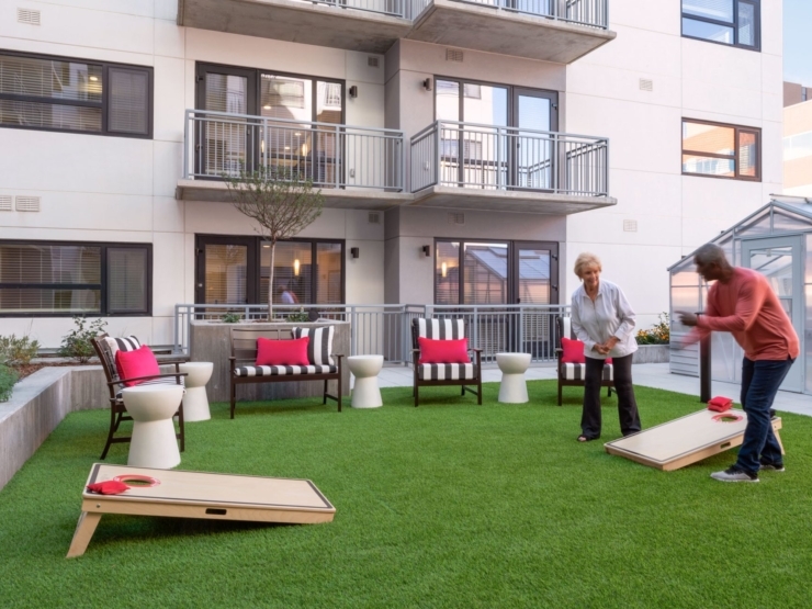 Engaging residents enjoy a lively game outdoors, surrounded by vibrant seating and lush greenery.