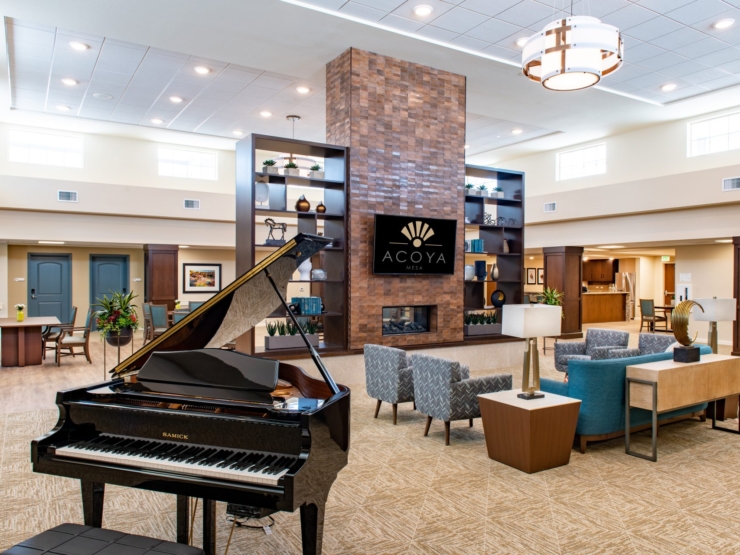 Bright and inviting, this community space features a welcoming piano, stylish seating, and a warm atmosphere.